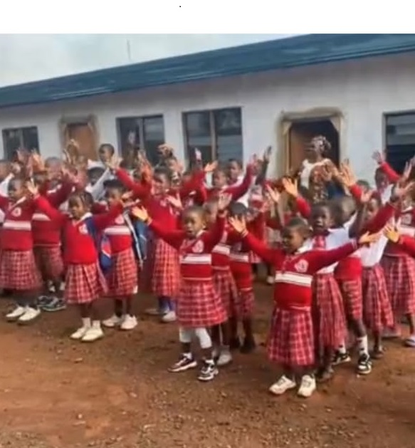 Élèves en uniforme rouge chantant dans la cour de l'école